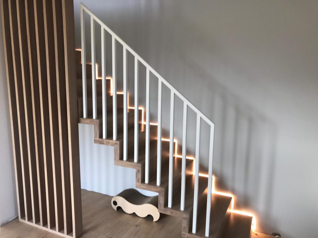 Nowoczesne schody dywanowe z białą balustradą o podświetleniem