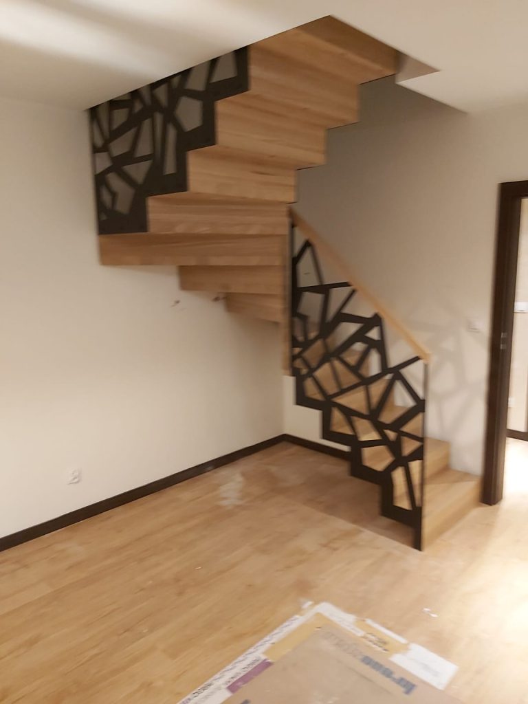 Drewniane schody dywanowe z czarną balustradą